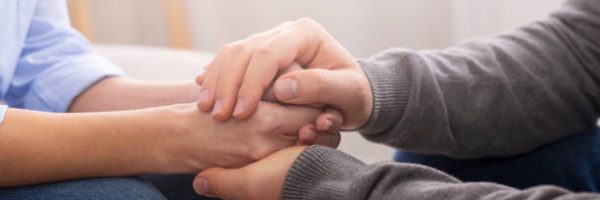 Compassion and concern concept. Psychiatrist supporting his patient hands during therapy