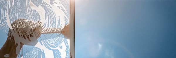 Window cleaner using a squeegee to wash a window with clear blue sky