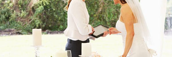 Bride With Wedding Planner In Marquee Using A Digital Tablet